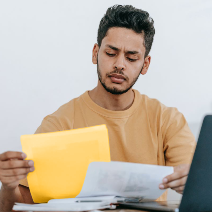 A man sitting at a table with documents and a laptop.