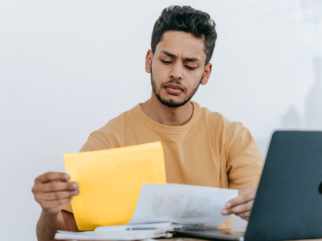 A man sitting at a table with documents and a laptop.