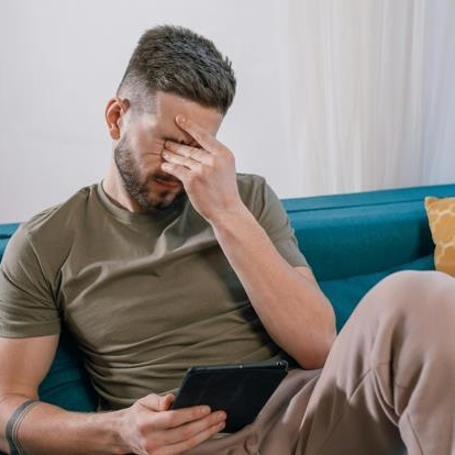 Newly unemployed man sitting on sofa stressed about his financial situation
