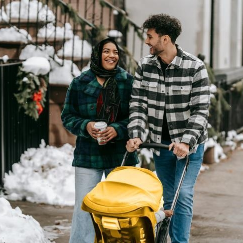 Couple walking outdoors and pushing a stroller after preparing for parental leave with a baby budget