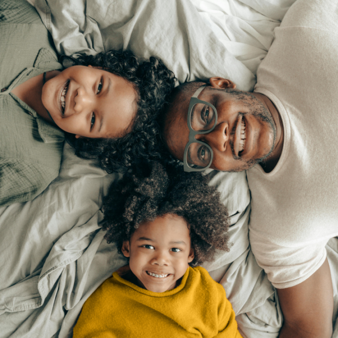 Father and two kids lying down and smiling after family financial meeting