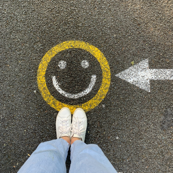 Person standing on the road with a smiley face painted on it, symbolizing the joy of debt relief