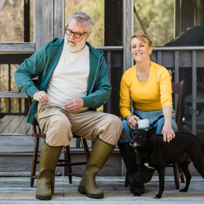 Retired man and woman sitting outside with two pet dogs