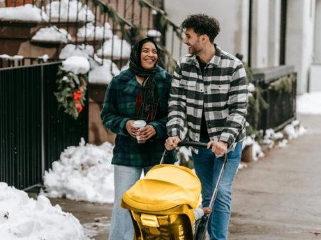 Couple walking outdoors and pushing a stroller after preparing for parental leave with a baby budget