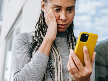 Woman nervously looking at phone receiving a collection call