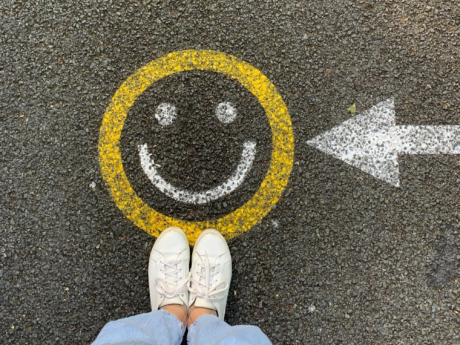 Person standing on the road with a smiley face painted on it, symbolizing the joy of debt relief