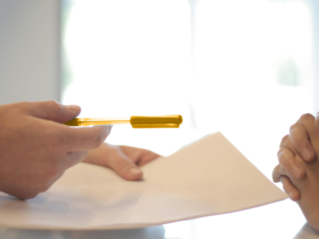 Une personne tend un stylo à quelqu'un qui fait face à une dette de prêt sur salaire