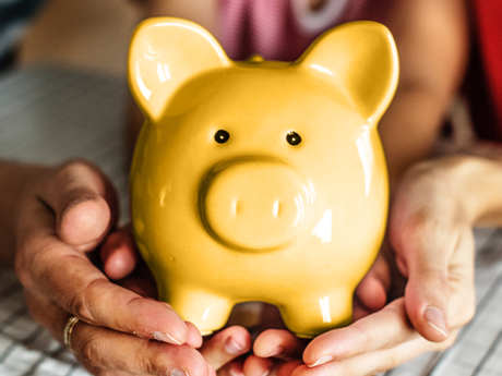 Two hands holding a yellow piggy bank, symbolizing the importance of financial goal setting