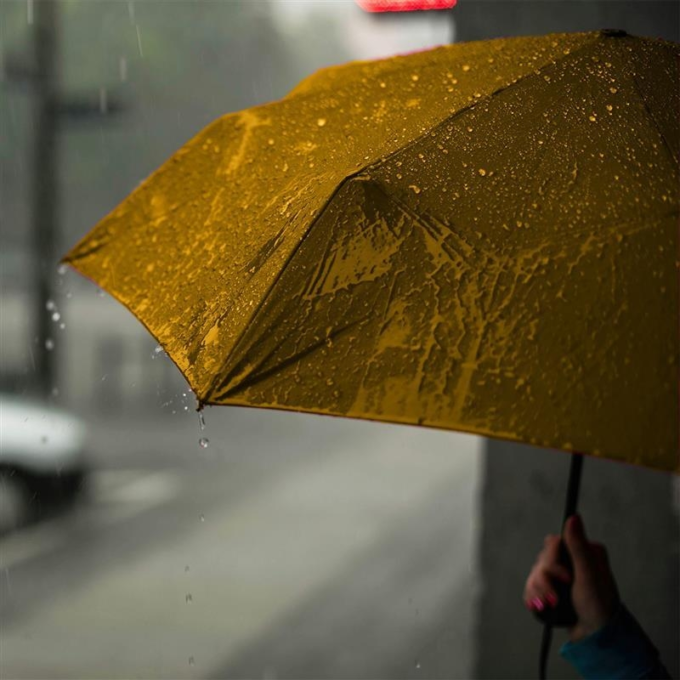 Person holding a yellow umbrella while walking down the street on a rainy day.