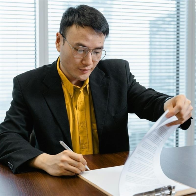 A man wearing a suit signing paperwork