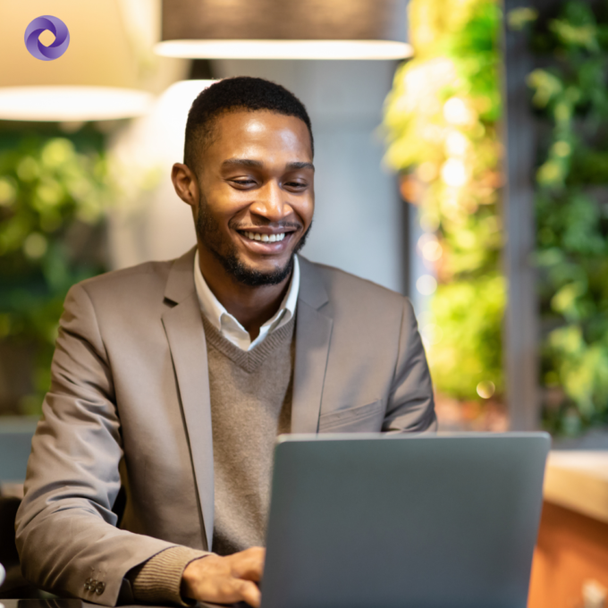 Man sitting at a desk with a laptop smiling