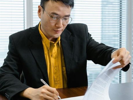 A man wearing a suit signing paperwork